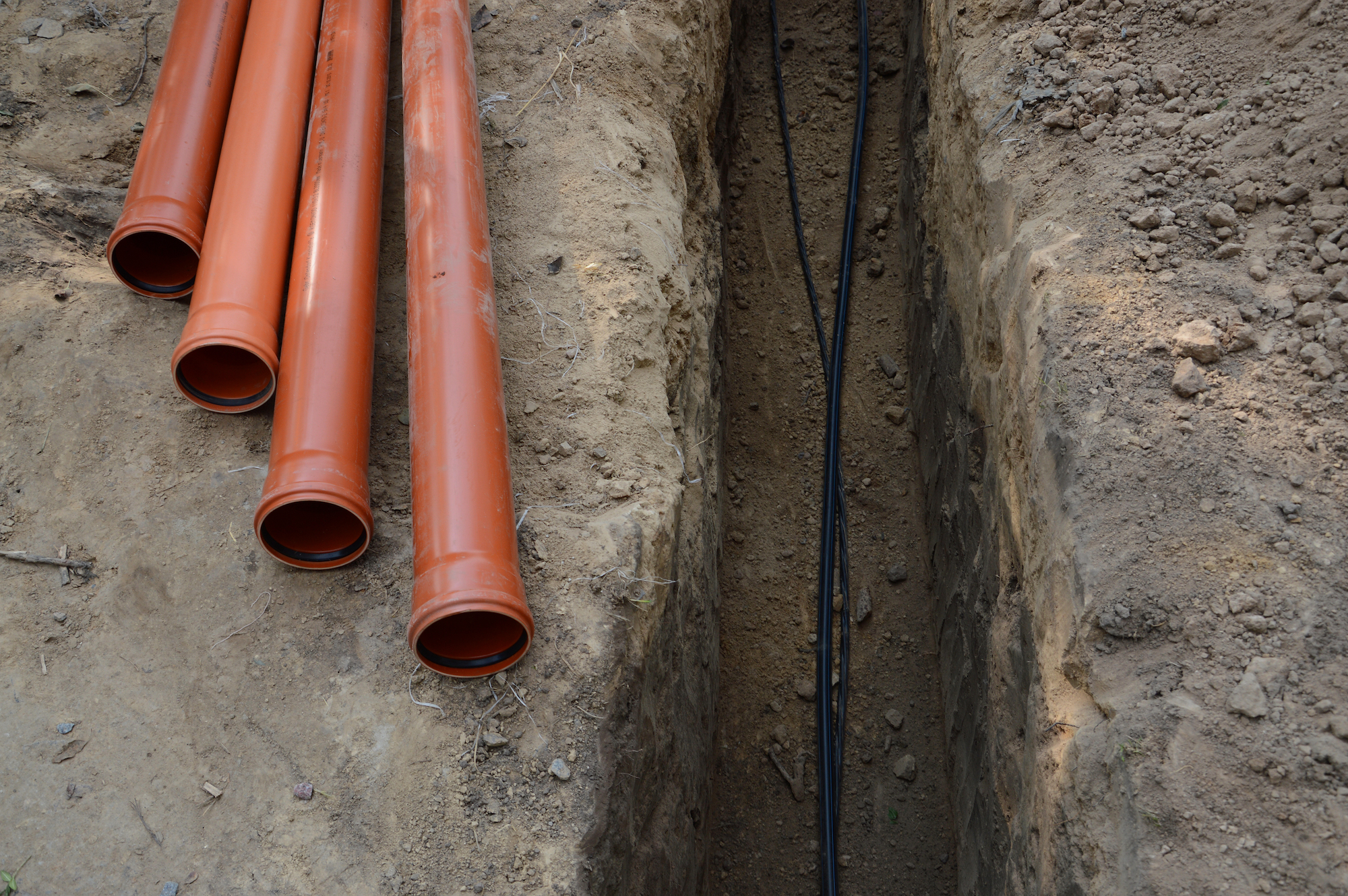 Safety,Supply,To,House,New,Insulated,Internet,,Gas,Cord,,Red Safety supply to house new insulated internet, gas cord, red metal-plastic tap system construction lay in pit dug in garden. Top view with space for text on grey clay earth. Telecom service industry